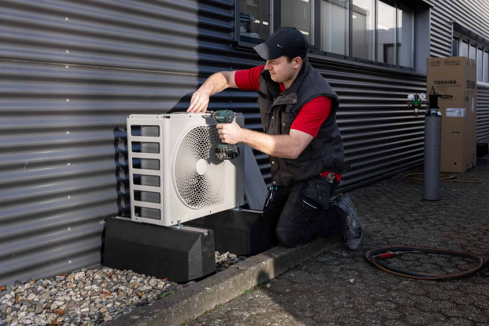 Technicus voert onderhoud uit aan buitenunit airco.