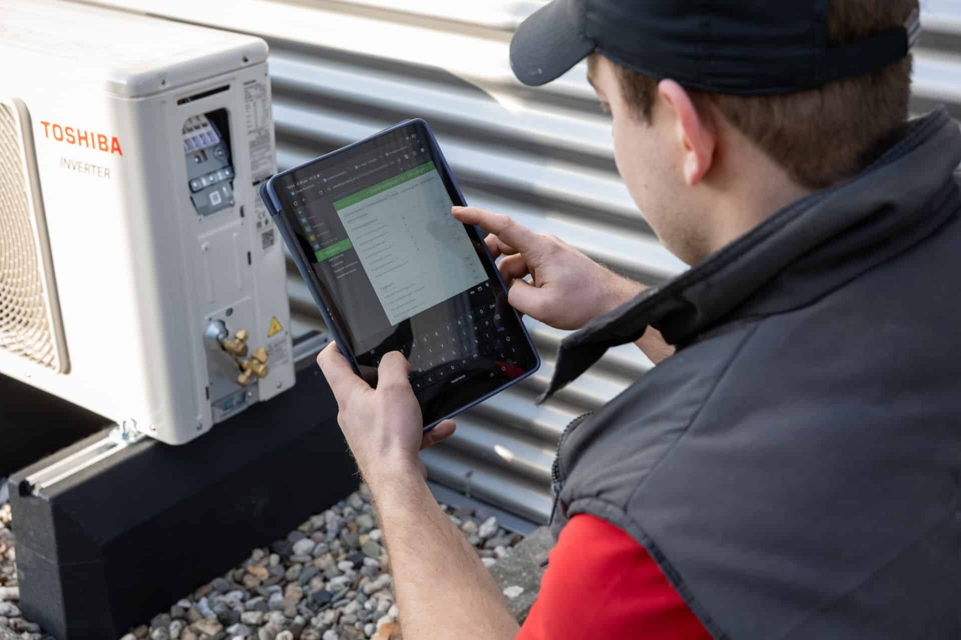 Technicus gebruikt tablet voor onderhoud van airconditioning.